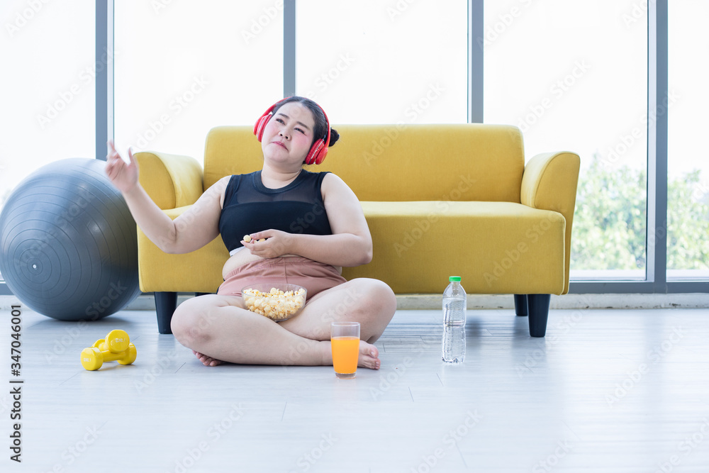 Asian Overweight Woman Using Tablet And Wearing Headphone For Listening Music And She Is 