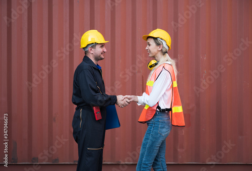 Happy dealing shaking hands two foreman man & woman worker working checking at Container cargo harbor to loading containers. Dock male and female Logistics import export shipping concept.