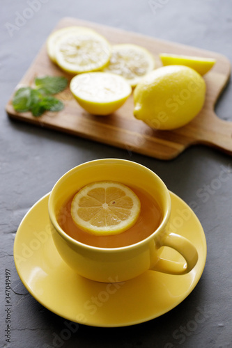 cup of tea with fresh yellow lemons on black background