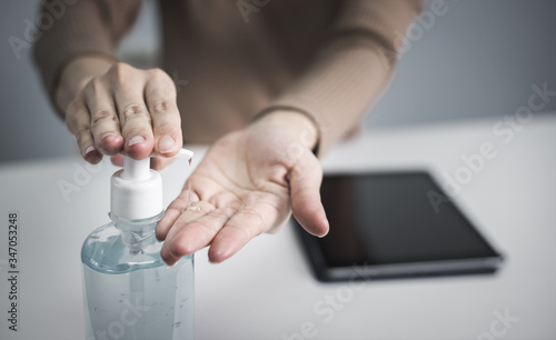 Business woman washing his hands with an alcohol gel in a pump-like bottle to prevent the spread of the Covid-19 virus.