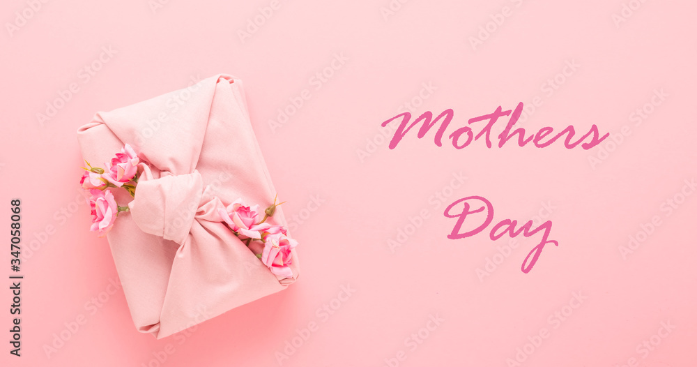 Holiday gift wrapping fabric Furoshiki style on a pink background lettering Mother's Day. Zero Waste Life Concept. Holiday gift wrapping fabric Furoshiki style on a pink background lettering Mother's Day. Zero Waste Life Concept.