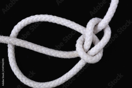 A white rope tied with bowline knot on black background.