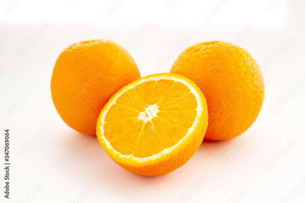 Three oranges on a white background, one cut in half Three oranges on a white background, one cut in half