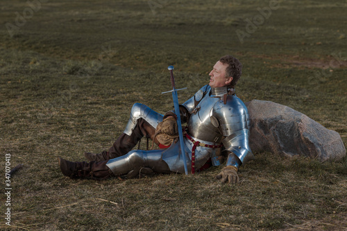 Vászonkép Knight infantryman in armor and with a sword resting on the battlefield