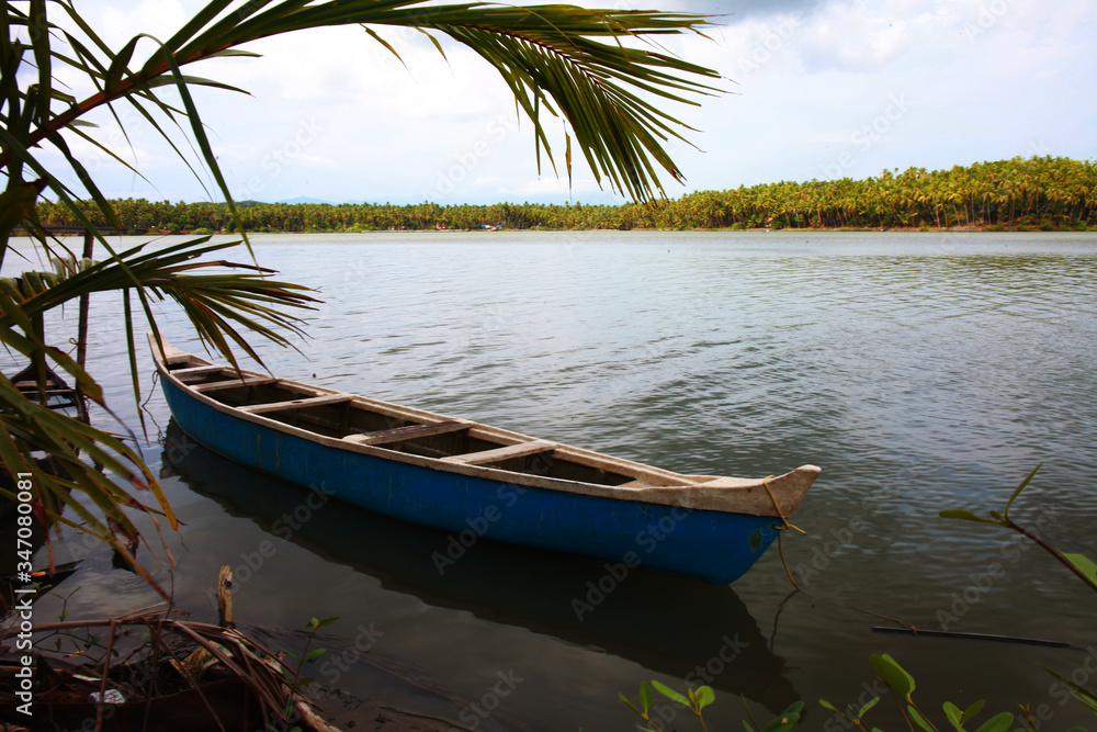 Lonely canoe on the riverbanks of Ponoor puzha. Aesthetic view of the Kerala beauty, depicting the elegance, serenity and harmony of the nature.