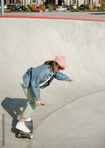 Young woman doing skateboarding trick outdoor in skate park 