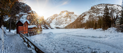 Panoramic view to the mountainscape and frozen lake Lago Di Braies, Pragser Wildsee, in the Italian Dolomites on a cold winter sunrise photo
