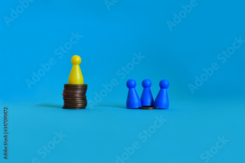 Pawns standing on piles of different sizes of coins. Income and economic inequality concept. photo