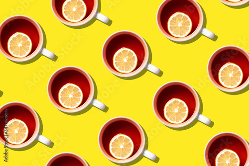 Pattern of tea cups with lemon on yellow background. Top view. Copy space. Creative design for packaging. Autumn or winter season concept