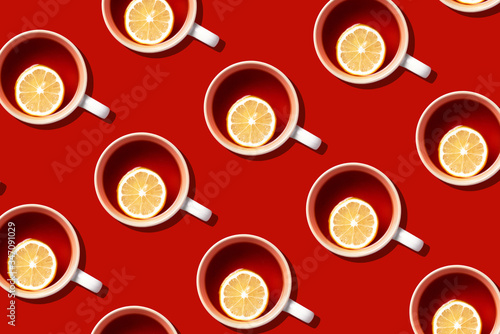 Pattern of tea cups with lemon on yellow background. Top view. Copy space. Creative design for packaging. Autumn or winter season concept
