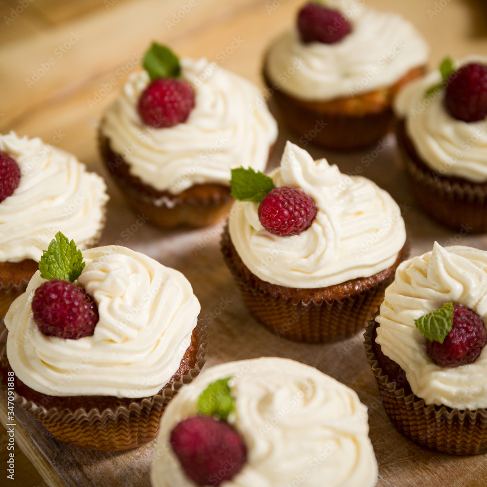 Delicious cupcakes with raspberry cream and a leaf of mint are on a stand. Healthy food for the holiday and party or birthday. Selective focus Delicious cupcakes with raspberry cream and a leaf of mint are on a stand. Healthy food for the holiday and party or birthday. Selective focus