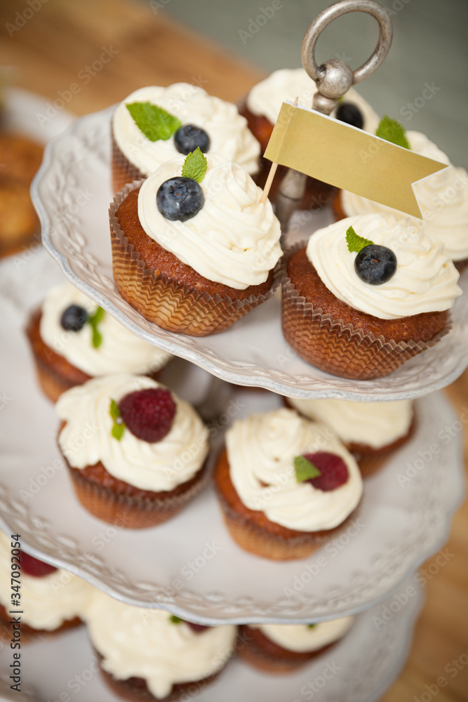 Delicious cupcakes stand on a multi-story stand with a flag at the very top. Healthy food for the holiday and party or birthday. View from above Delicious cupcakes stand on a multi-story stand with a flag at the very top. Healthy food for the holiday and party or birthday. View from above