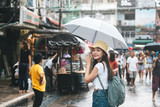 Young adult asian traveller hold umbrella when rainy at walking street.