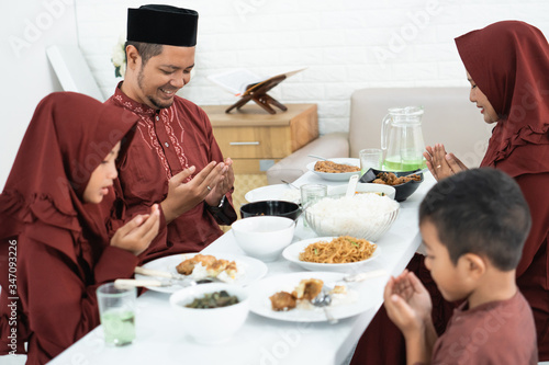 Muslim family sit and pray when breaking fast together at home