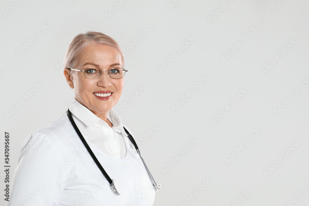 Portrait of mature doctor with stethoscope on light grey background. Space for text Portrait of mature doctor with stethoscope on light grey background. Space for text