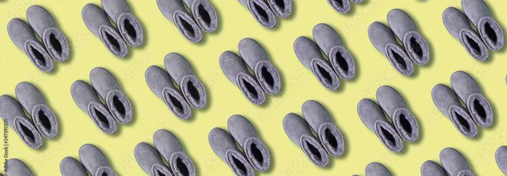 Pattern of grey ugg boots on yellow background. Creative design for packaging. Winter concept. Christmas and new year holiday. Pattern of grey ugg boots on yellow background. Creative design for packaging. Winter concept. Christmas and new year holiday.