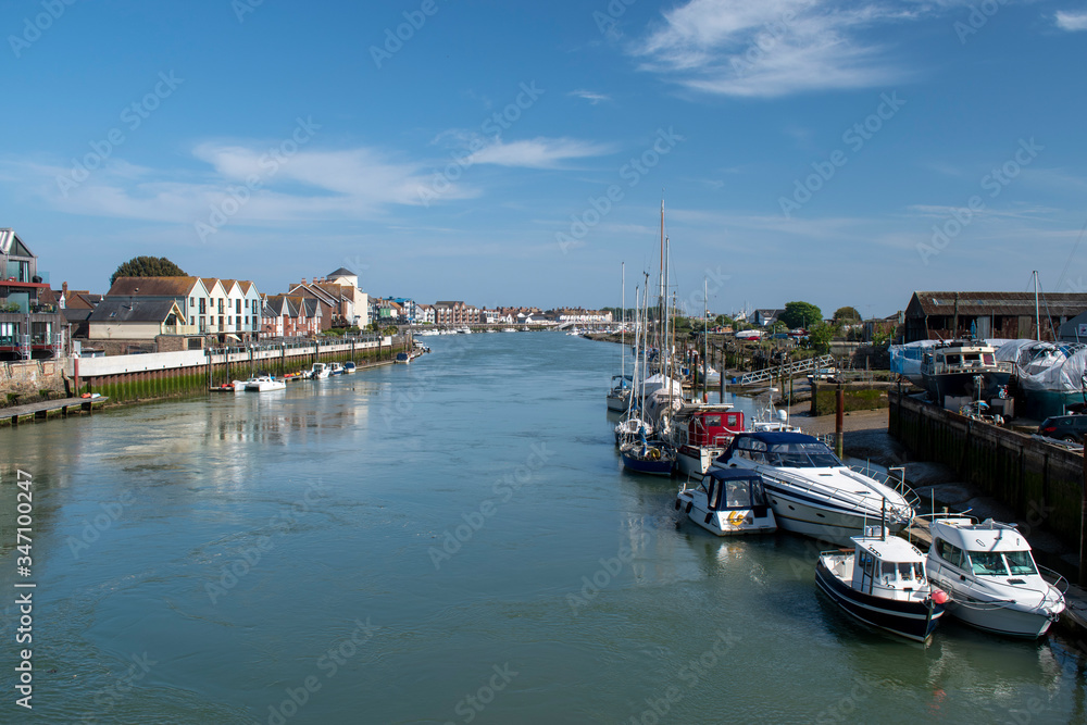 The beautiful River Arun meandering it's way past Littlehampton with boats moored on each side on a sunny day in May.