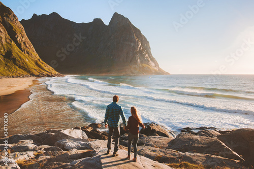 Couple walking on Kvalvika beach travel romantic vacations outdoor healthy lifestyle man and woman together enjoying ocean and rocks landscape in Norway Lofoten islands summer trip © EVERST