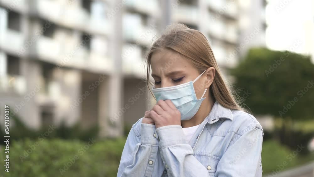 Woman coughs in medical mask on empty city street. Portait, pandemic team Woman coughs in medical mask on empty city street. Portait, pandemic team
