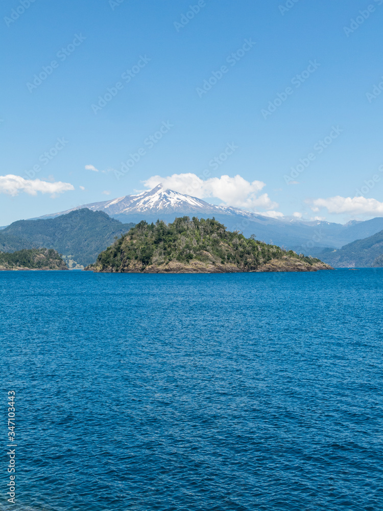 The amazing Choshuenco Volcano surrounded by clouds, over the waters of Lake Panguipulli, in southern Chile.