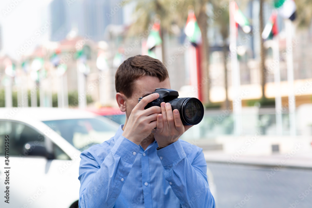 Photographer tourist on the streets of Dubai. A male photographer paparazi in a blue shirt is watching an object taking photos