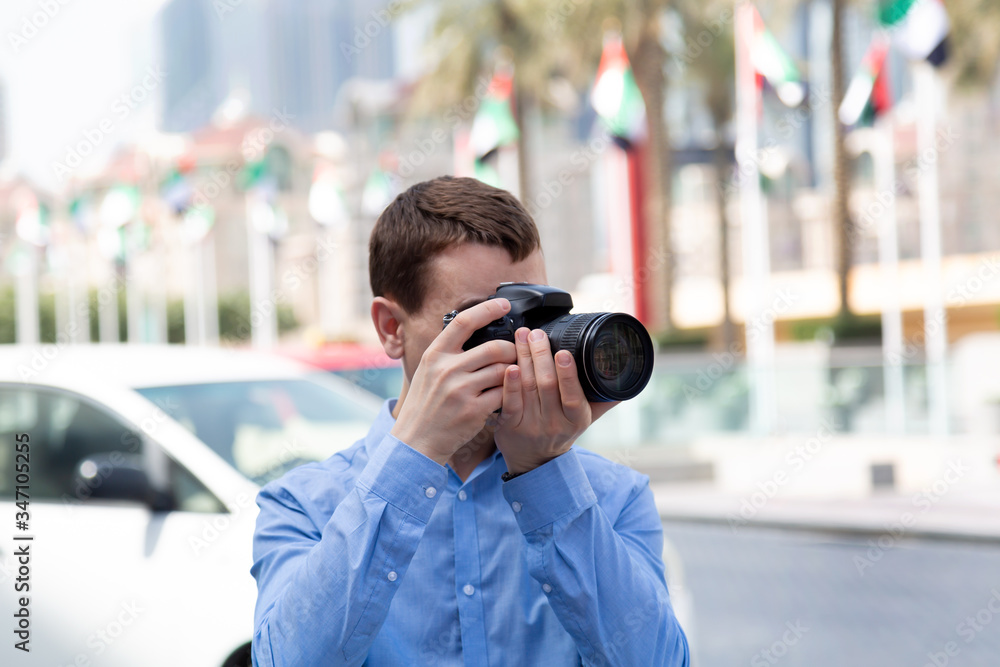 Photographer tourist on the streets of Dubai. A male photographer paparazi in a blue shirt is watching an object taking photos Photographer tourist on the streets of Dubai. A male photographer paparazi in a blue shirt is watching an object taking photos