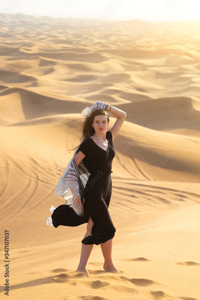 Girl model poses for the photographer in the desert. Caucasian woman 20-25 years old in black clothes dancing in hot desert. Girl model poses for the photographer in the desert. Caucasian woman 20-25 years old in black clothes dancing in hot desert.