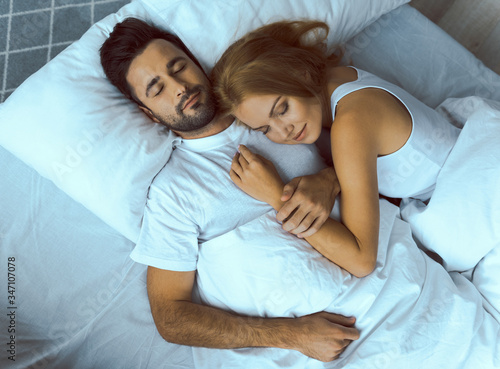 Happy young couple sleeping in embraces in morning