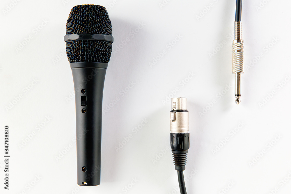 Obraz premium Top view of black microphone with XLR and mono jack cable, isolated on white background.
