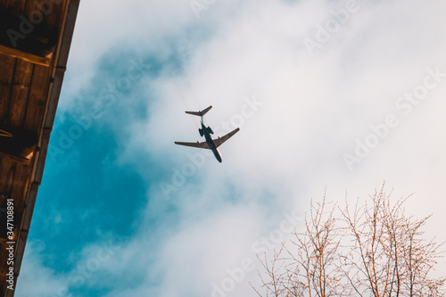 Plane flies at low altitude above the house. airplane in blue sky.