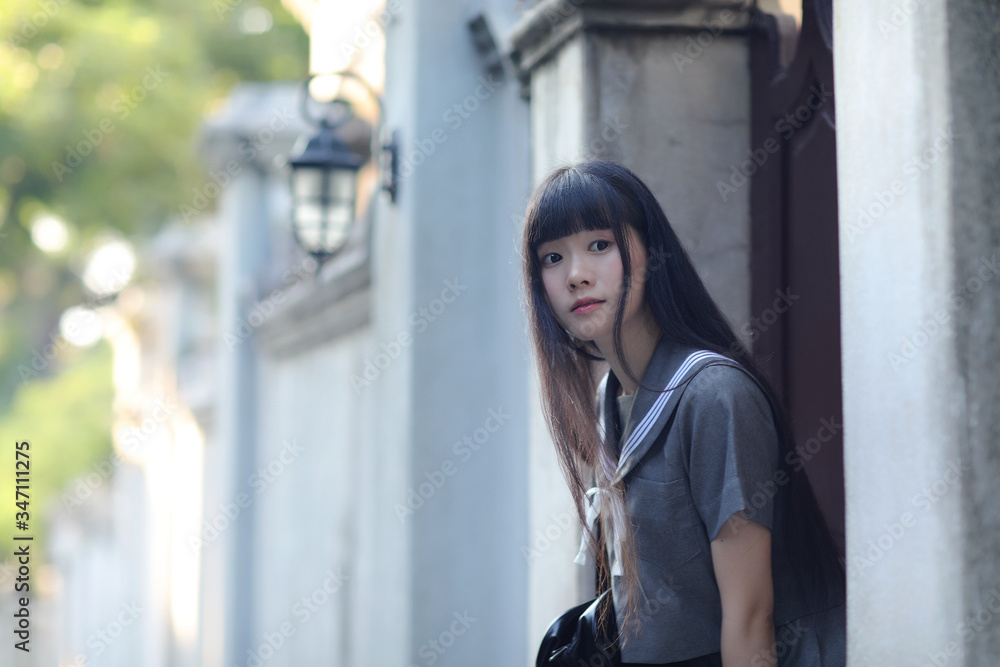 A beautiful Asian woman in student dress looking back on the road A beautiful Asian woman in student dress looking back on the road