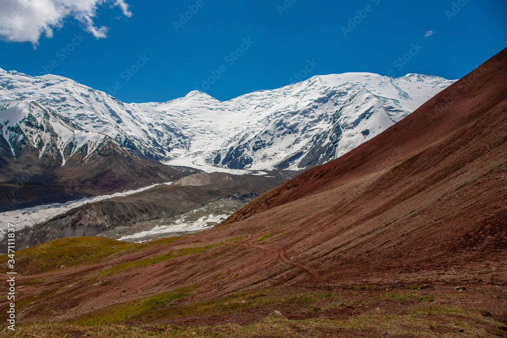 Snowy mountain peaks. Scenic landscape. Beautiful nature. Red sand.