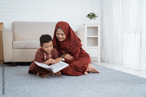 Asian boy learns the Al-Quran with her mother at home photo