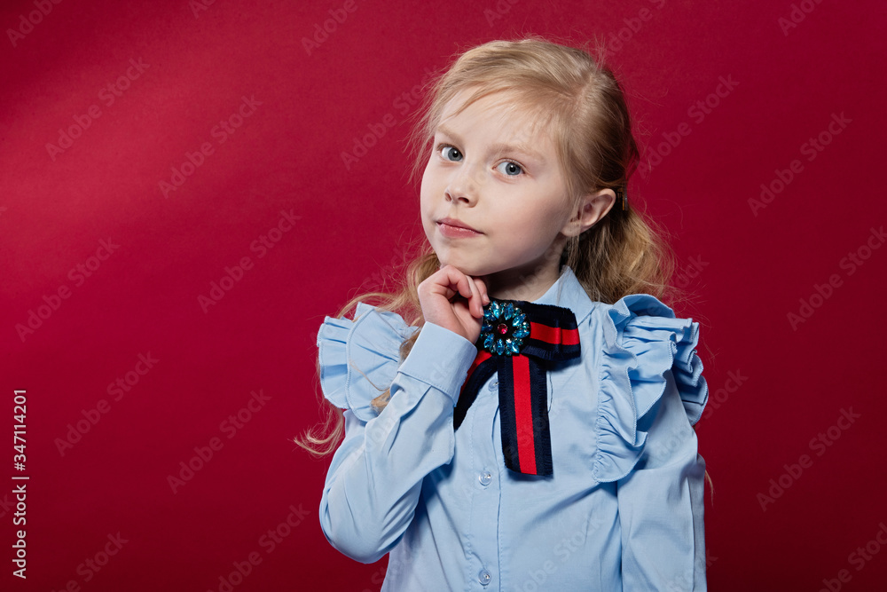 portrait of a little girl on a red background, a girl in a lips shirt, look in front, a pleasant emotion on her face portrait of a little girl on a red background, a girl in a lips shirt, look in front, a pleasant emotion on her face