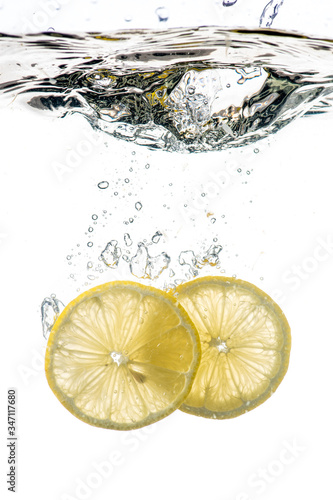whole and sliced lemon falling under water with a splash and bubbles on a white or black background