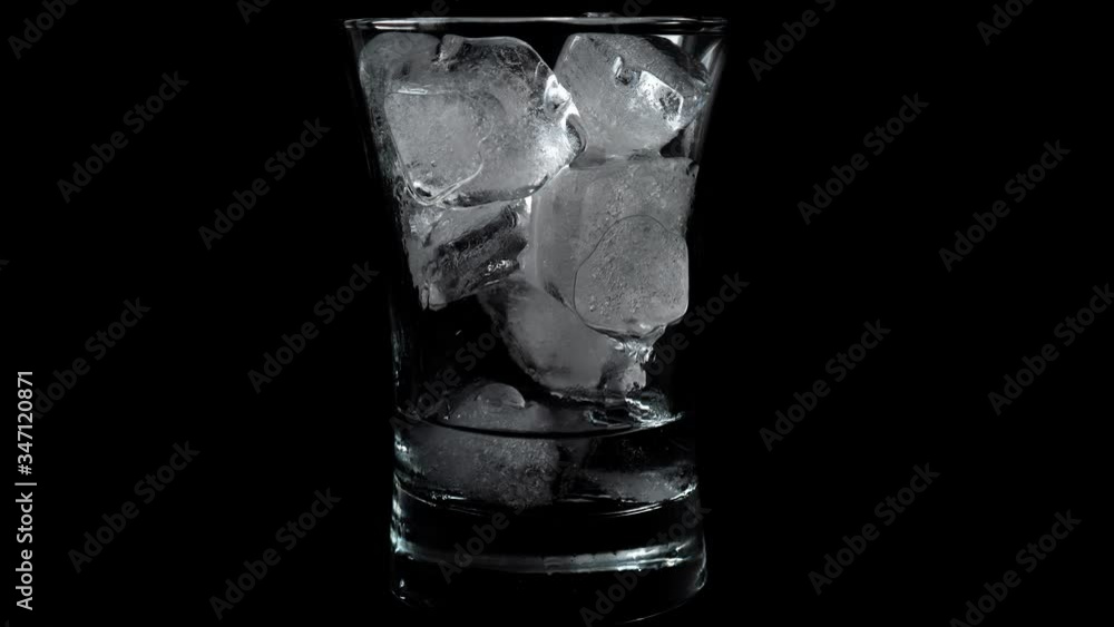 Time lapse of melting ice cubes in glass with black background Time lapse of melting ice cubes in glass with black background
