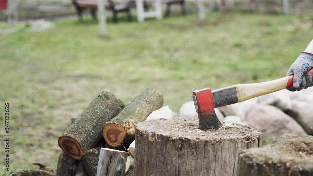 A man is chopping wood with an axe in the open air.Manual chopping of firewood A man is chopping wood with an axe in the open air.Manual chopping of firewood