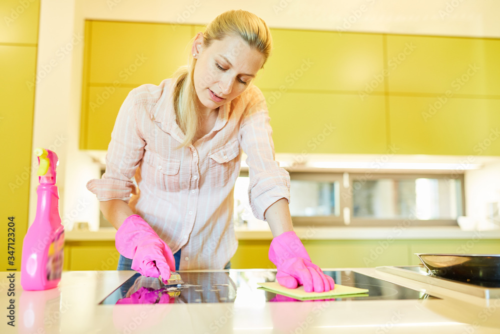 Putzfrau mit Schaber beim Kochfeld reinigen - obrazy, fototapety, plakaty 