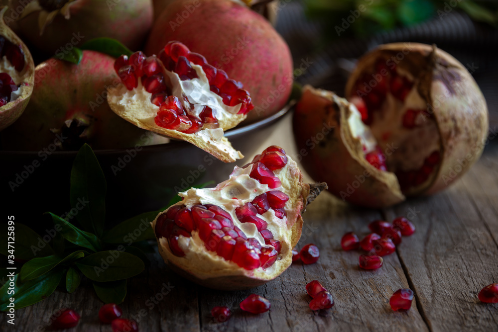 Fresh organic pomegranate fruit with leaves on dark background Fresh organic pomegranate fruit with leaves on dark background