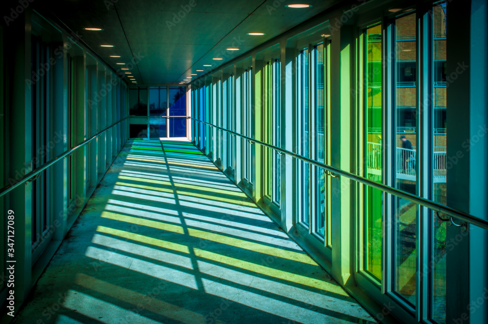 Low green and blue light with shadows form on the interior of a stained glass public pedestrian walkway Low green and blue light with shadows form on the interior of a stained glass public pedestrian walkway