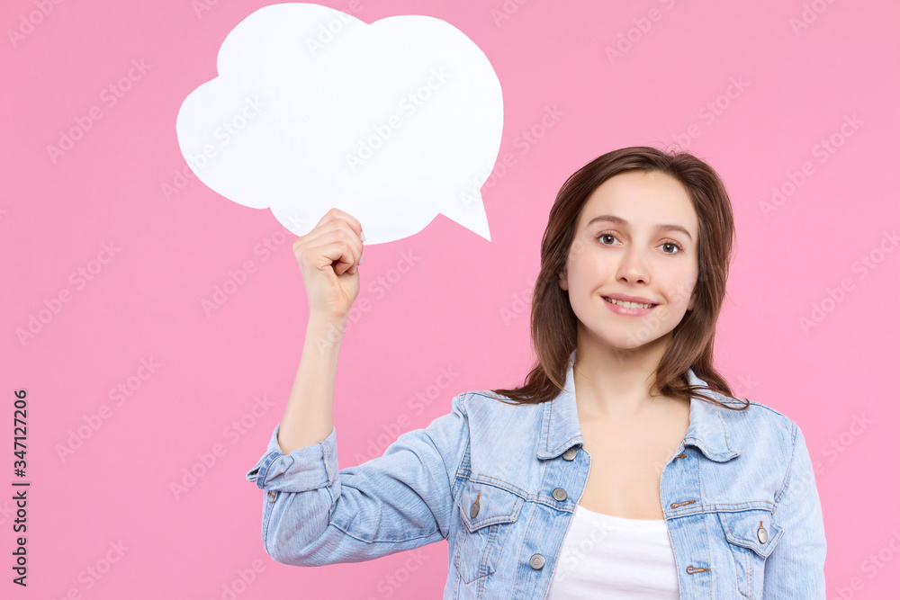 Pretty girl in white t-shirt, denim jacket is holding in hand paper decorative thinking, speaking cloud. Young woman is smiling and dreaming on pink background. Emotional portrait concept. Pretty girl in white t-shirt, denim jacket is holding in hand paper decorative thinking, speaking cloud. Young woman is smiling and dreaming on pink background. Emotional portrait concept.