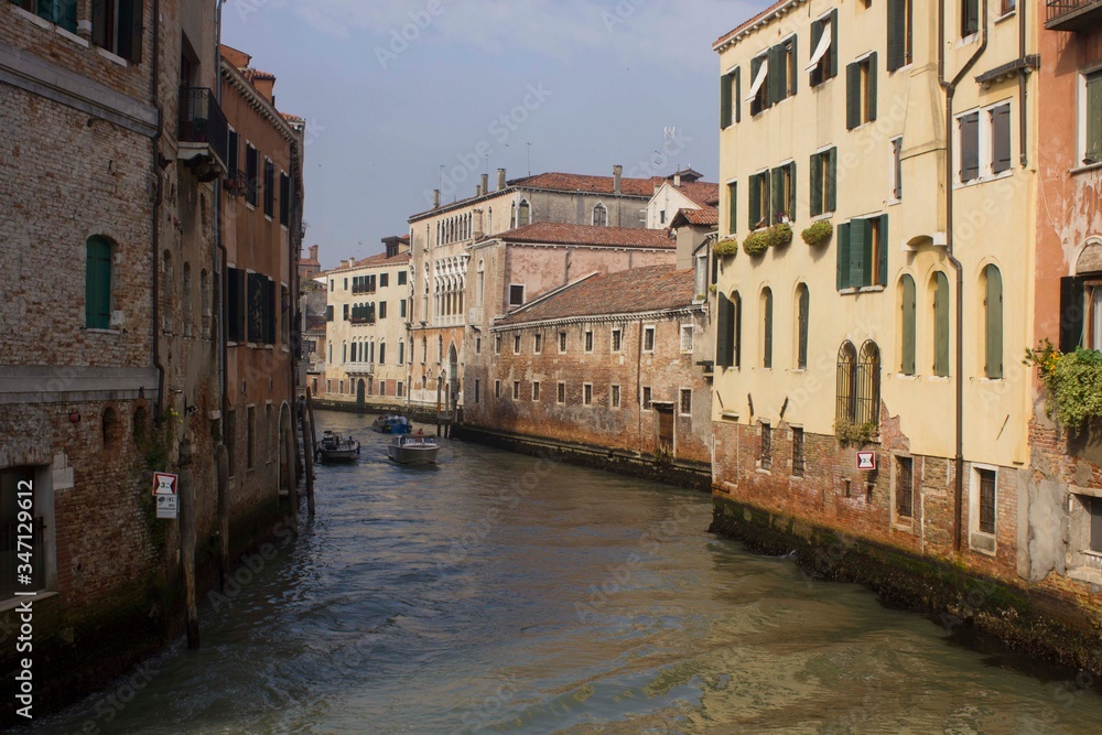 Traditional canal in Venice with motoboat crossing it