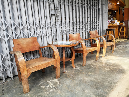 Many wooden chairs are waiting for coffee lovers to sit and rest  placed in front of the old style metal doors as the backdrop.