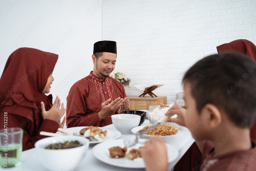 Muslim family sit and pray when breaking fast together at home Muslim family sit and pray when breaking fast together at home