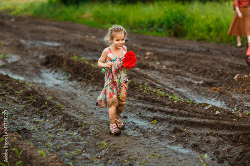 little girl goes in dirty dirt road after rain. © andrey