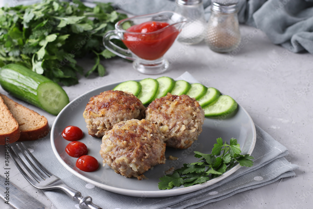 Beef cutlets served with cucumber and tomato sauce on a gray plate on gray concrete background, Horizontal format