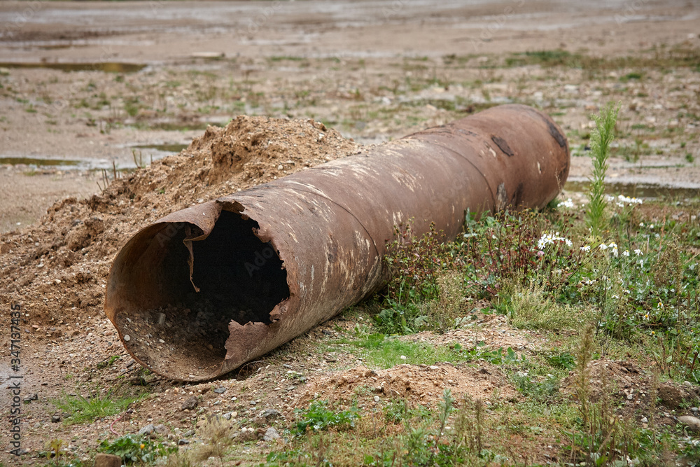 Old rusty pipe lying on the green grass Old rusty pipe lying on the green grass
