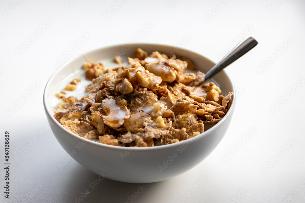 Schüssel mit gesundem Müsli, Cornflakes, Walnüssen, Honig, Milch und Löffel ist bereit fürs Frühstück mit Cerealien, Cornflakes und Müsli als gesunde Mahlzeit und Ernährung am Frühstückstisch Schüssel mit gesundem Müsli, Cornflakes, Walnüssen, Honig, Milch und Löffel ist bereit fürs Frühstück mit Cerealien, Cornflakes und Müsli als gesunde Mahlzeit und Ernährung am Frühstückstisch