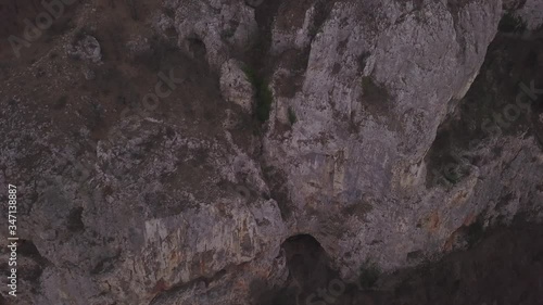 Aerial view of natural arch and cave of Casa Zmeului, part of the Via Ferrata, Iron Way, in Romania. Popular hiking and rock climbing destination. Steep rock walls with fading light shining. photo