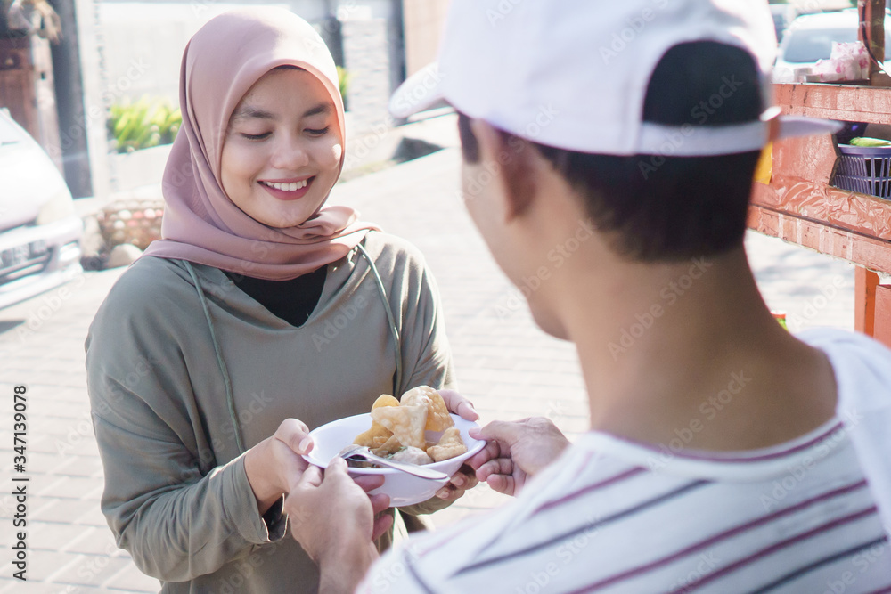 street food vendor handing a bowl of bakso or meatball to customer